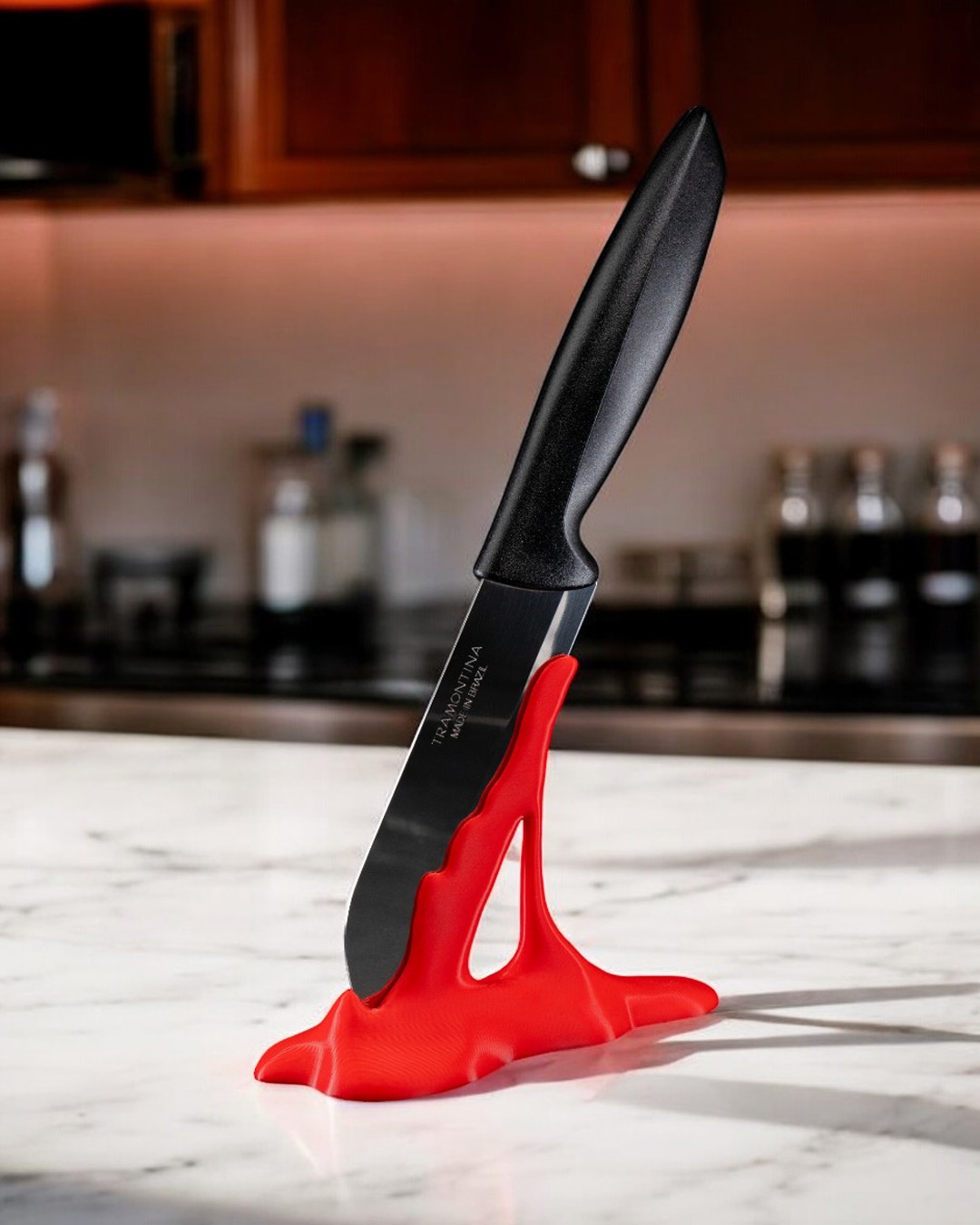 Black kitchen knife with a sleek design resting on a vibrant red silicone knife holder, set against a marble countertop in a modern kitchen. Ideal for showcasing contemporary kitchen tools and accessories.
