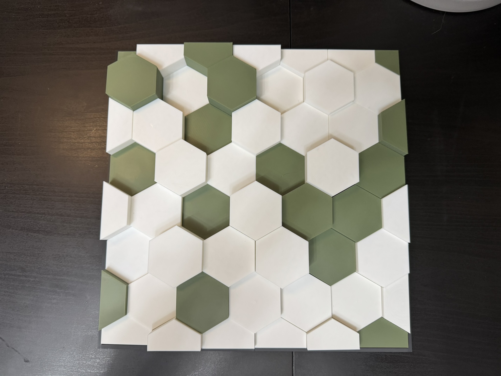 Hexagonal tiles arranged in a modern pattern featuring green and white colors on a dark surface, showcasing a stylish design suitable for interior decoration.