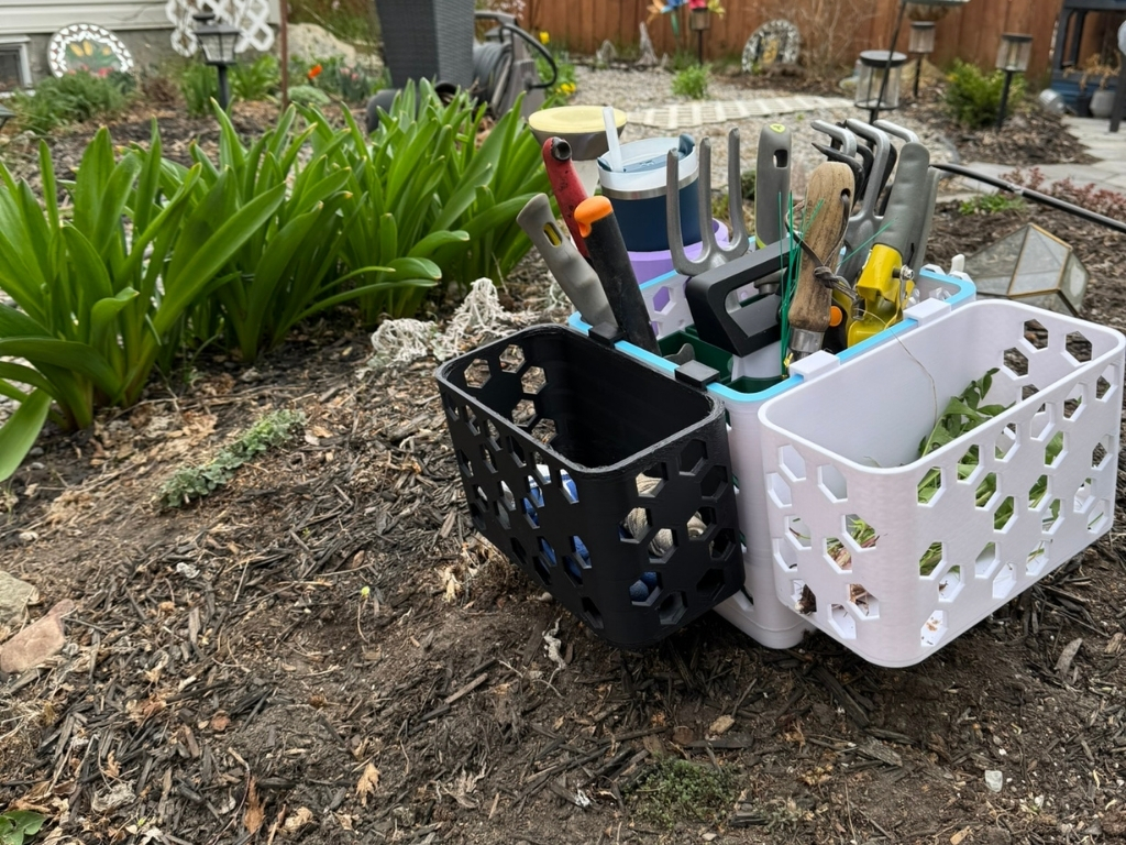 3 Gardening tools organized in black and white baskets on mulched garden soil, surrounded by green plants and garden decor.
